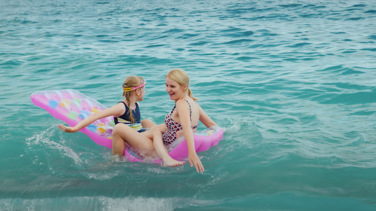 enormes olas del mar juegan con un colchón inflable una mujer con un niño pequeño se ríen y se divierten