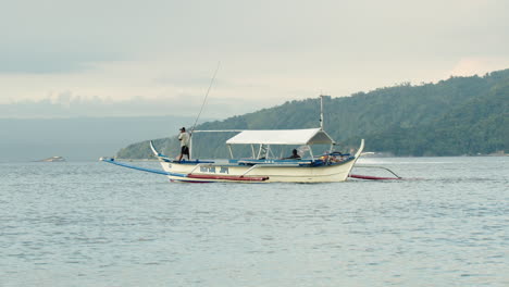 Toma-En-Cámara-Lenta-De-Un-Barco-De-Pesca-Saliendo-De-La-Orilla-Con-Una-Pequeña-Lancha-Rápida-A-Su-Lado