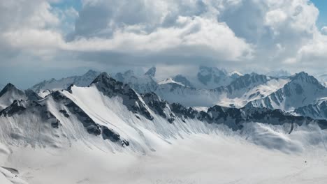 air flight through mountain clouds over beautiful snow-capped peaks of mountains and glaciers.