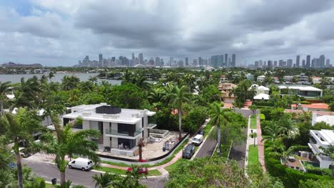 waterfront mansion in miami, florida with a private dock. venetian islands neighborhood with luxurious home and pool surrounded by palm trees. aerial reveal of biscayne bay and skyline.