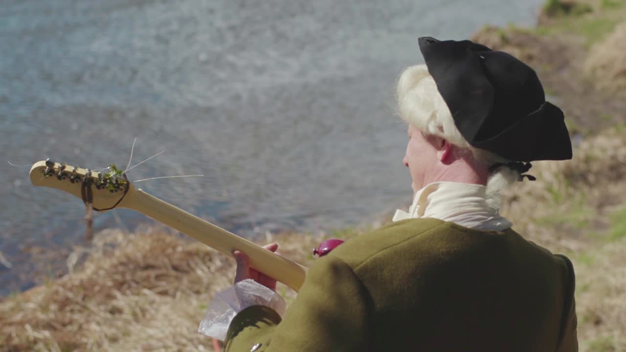 историческая фигура играет на гитаре у реки