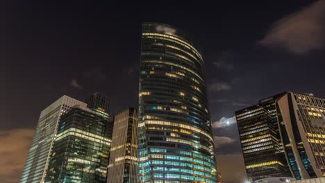 the moon at night making her way between towers of la defense business district paris