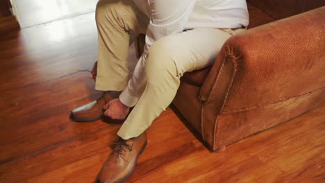 toma de ángulo alto de un hombre sentado atando los cordones de sus elegantes zapatos marrones