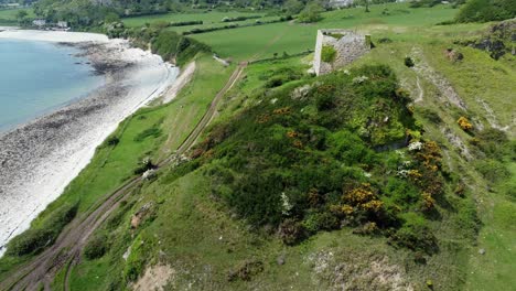 abandoned overgrown ivy covered desolate countryside historical welsh coastal brick factory mill aerial view lowering countryside reveal