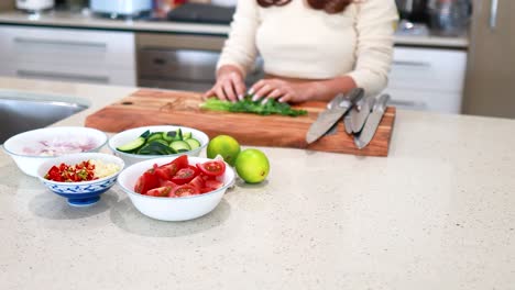 a person chops vegetables on a countertop in a well-lit kitchen, surrounded by fresh ingredients and utensils