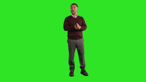 full length studio portrait of mature male teacher talking to class standing against green screen