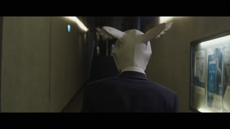 Man walking down a corridor with a rabbit head