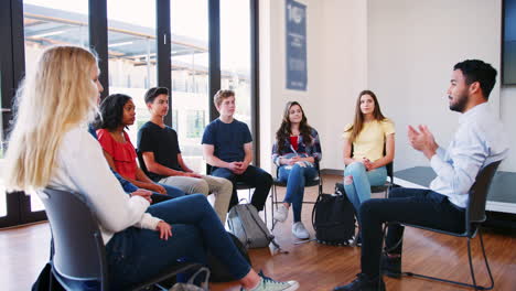 male tutor leading discussion group amongst high school pupils