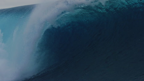 surfer dips below surface as icy blue clear water crashes into powerful dangerous barrel of wave