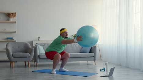 hombre haciendo ejercicio con una pelota de yoga en casa