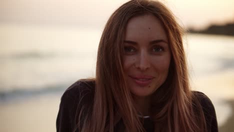 porträt eines blonden mädchens, das im herbst am strand steht und lächelt