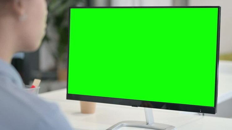 Set bagfra af afrikansk kvinde, der bruger en stationær computer med grøn chromakey-skærm