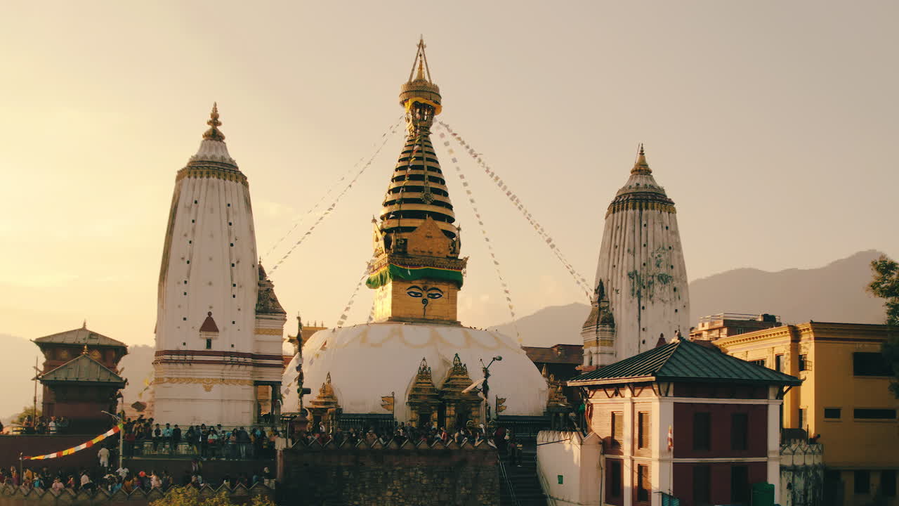 Ripresa mozzafiato con drone in parallasse dello Stupa di Swayambhunath, Kathmandu, conosciuto anche come Tempio delle Scimmie, all'ora d'oro. I raggi del tramonto illuminano l'antico tempio, rivelando gli intricati dettagli della struttura.