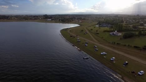 aerial drone shot of a quadricycle in the lake shore with a big cloud in the background