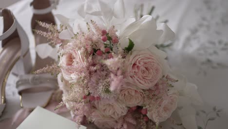 close up of pastel wedding bouquet and white heels on soft fabric background