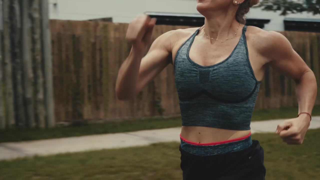 Donna in forma che fa jogging all'aperto lungo una staccionata di legno