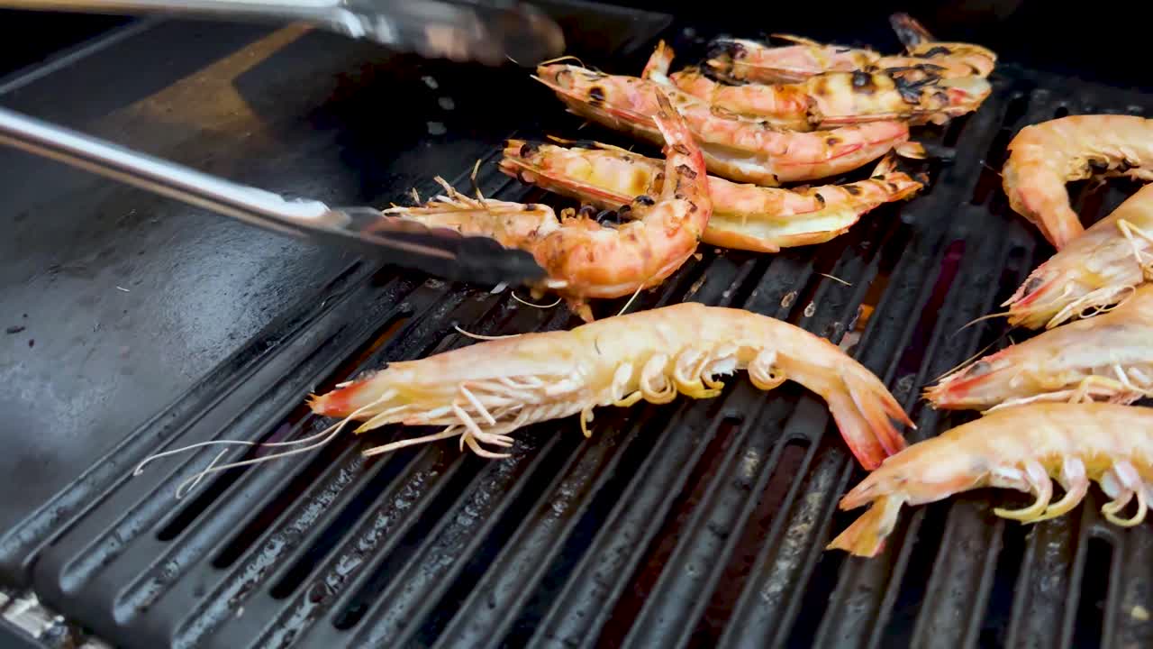 Prawns being grilled with tongs on barbecue