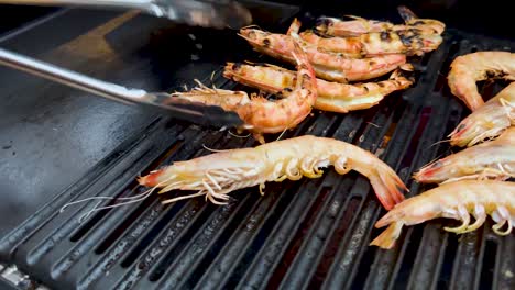 prawns being grilled with tongs on barbecue