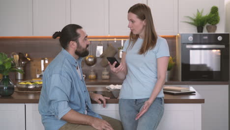 attractive woman gets angry looking at her bearded partner's cell phone