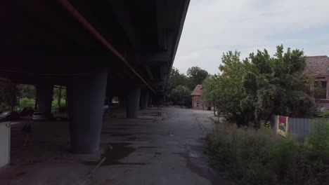 drone flying under bridge near half destroyed house