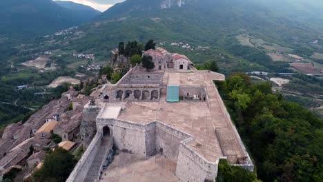 aerial pan forward shot of a fort on top of a small town in italy