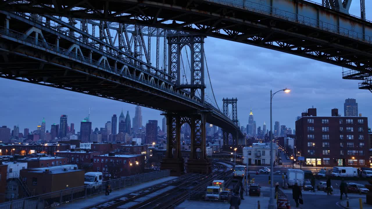 A video frame captures a low-angle view of a cityscape at dusk, featuring a bridge's intricate