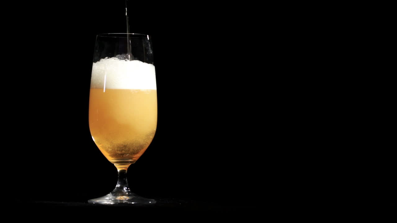 la cerveza se vierte en el vaso en negro