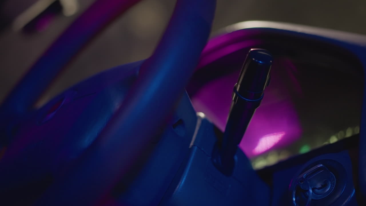 Salpicadero de coche iluminado con luces de neón por la noche, el conductor busca el contacto bajo un resplandor púrpura, primer plano del volante y la palanca de cambios, reflejos en la consola de cuero, atmósfera urbana íntima con farolas difusas