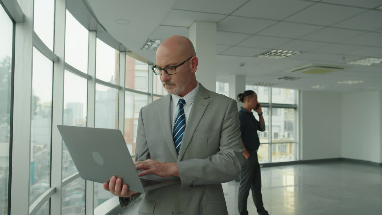 Mature Entrepreneur Typing on Laptop in Contemporary Office