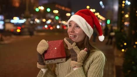 woman opening a christmas gift in the city at night