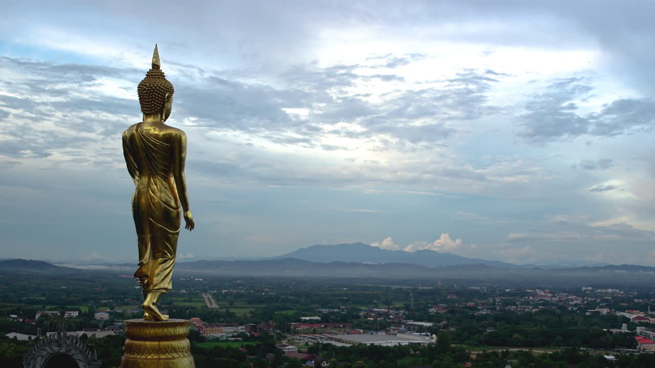 Dramatic Cumulus tropical cinematic cloudscape time lapse with Golden Buddha statue at Wat Phrathat Khao Noi over looking a city Nan Province