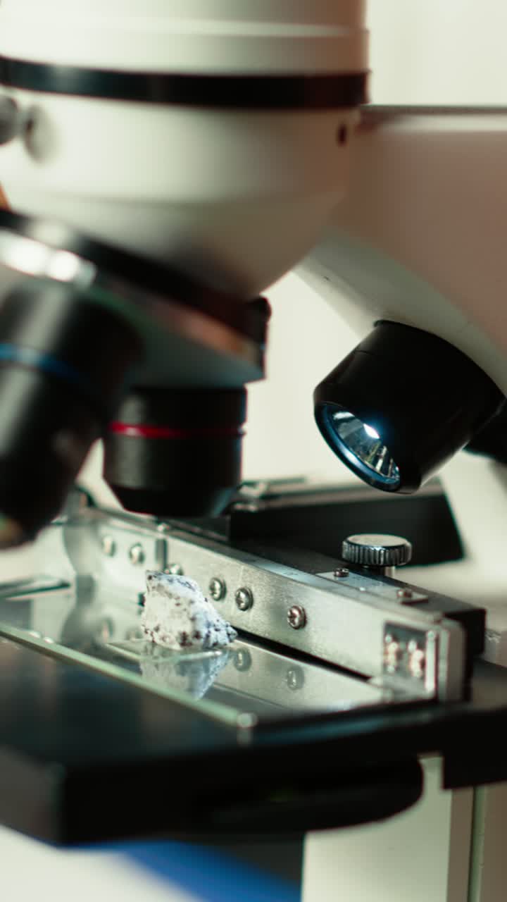 Close-up of Hand Placing Rock Sample on Microscope Stage