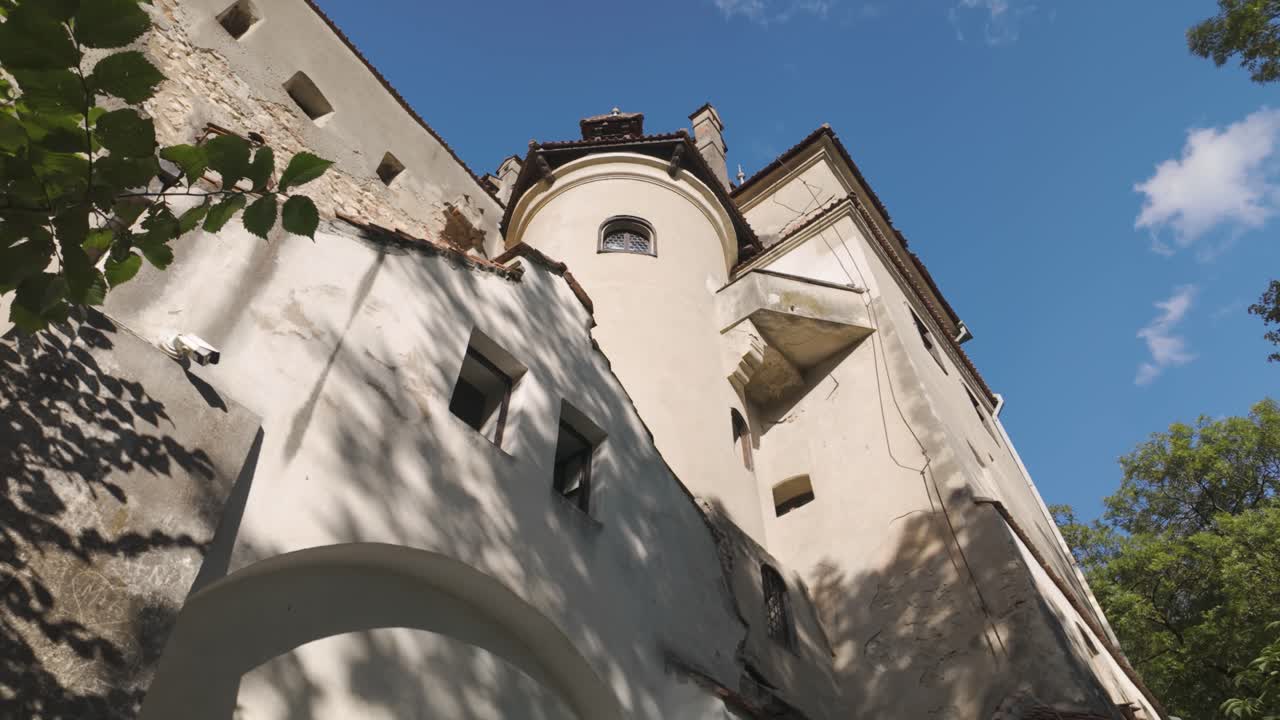 Scenic upward pan capturing the tower of Bran Castle rising against the sky