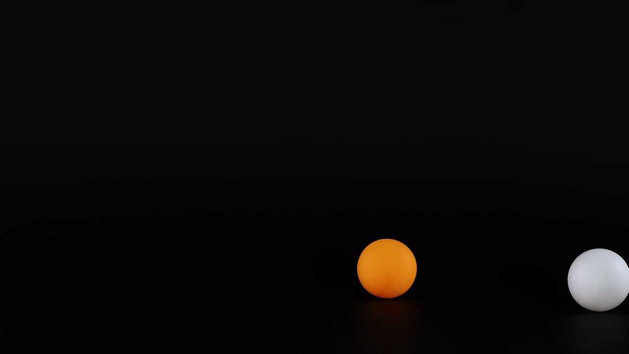 Colorful balls, including orange, pink, and white, are arranged dynamically against a dark background.