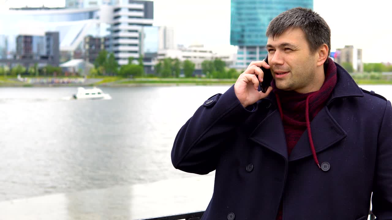 한 남자가 도시 풍경을 배경으로 드폰으로 이야기하고 있습니다.