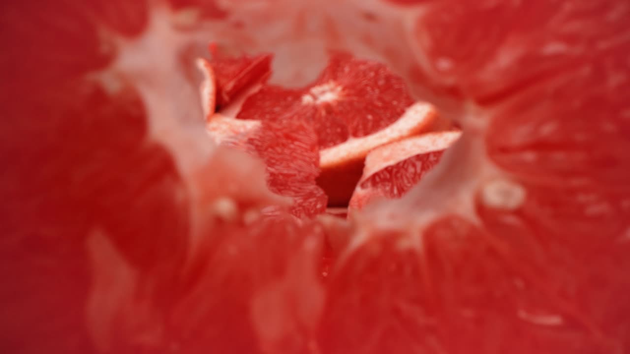Closeup pull away through the center of grapefruit slice as it falls over product food video 4k