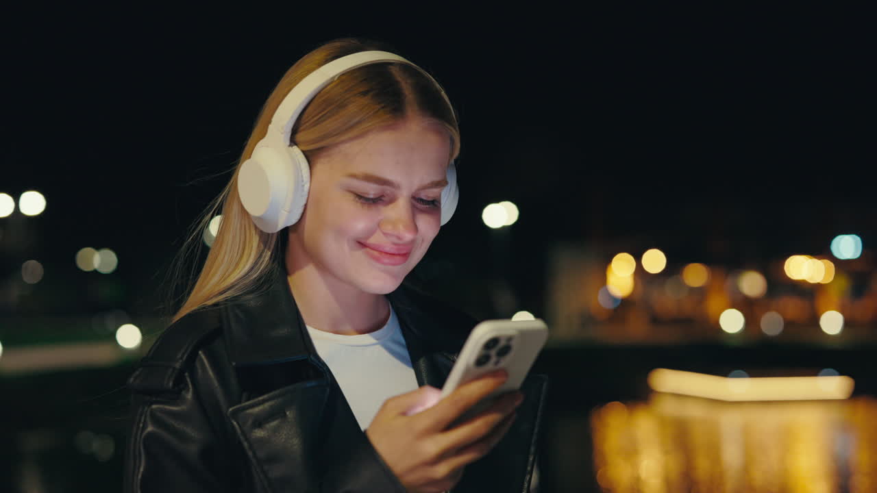 Donna con cuffie e smartphone di notte