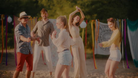happy friends dancing together at beach during sunset
