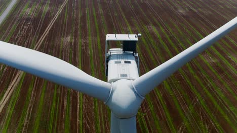 Windturbine-Mit-Propellern-Und-Kegel-Von-Einer-Luftdrohne,-Die-Mit-Neigungsansichten-Vor-Dem-Hintergrund-Von-Ackerland-Aufsteigt