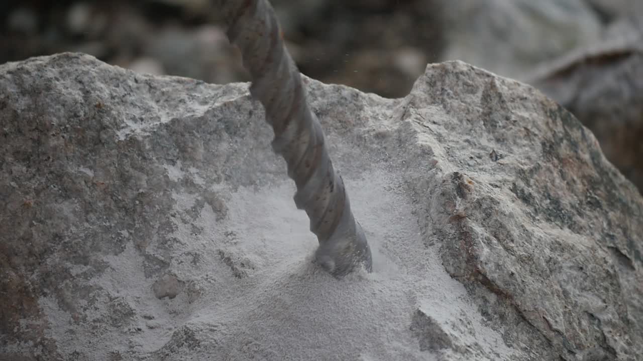 Close up of a driller digging a hole into a rock in slow motion