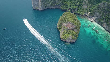 Backside-of-Maya-Bay-Beach-Lagoon,-Koh-Phi-Phi-Leh-Island,-Thailand,-Aerial-View-on-Speedboat-in-Tropical-Sea-by-Limestone-Cliffs