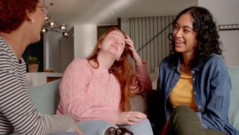laughing and chatting, diverse female friends hanging out on couch in living room