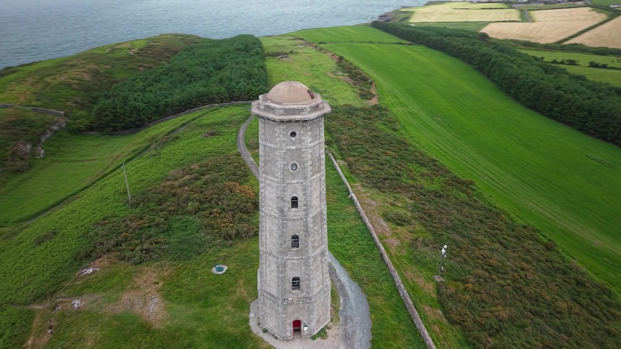 Dynamisk luftpanorama af Wicklow Head Front Fyrs historiske tårn og barske kyst
