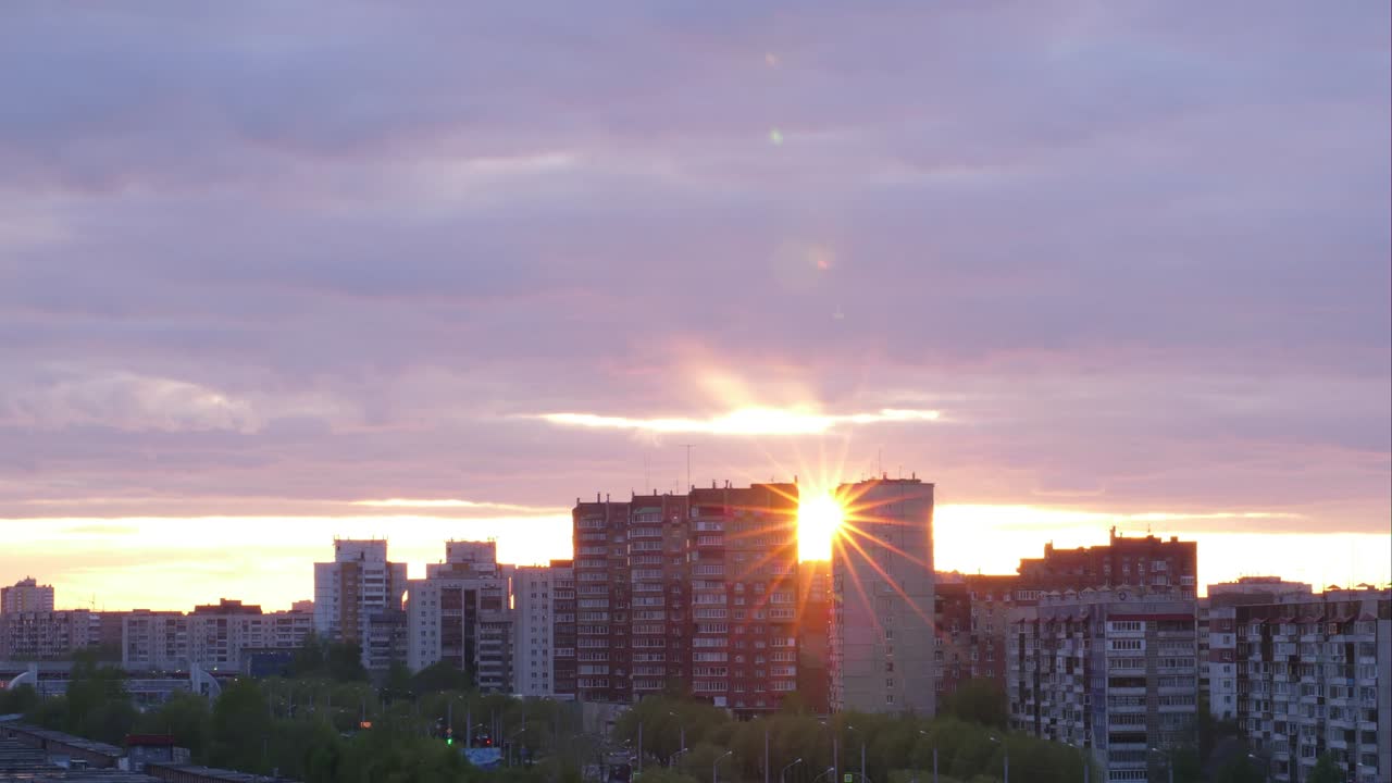 Bela vista em timelapse do céu do pôr do sol na cidade com edifícios. Reflexo do raio de sol