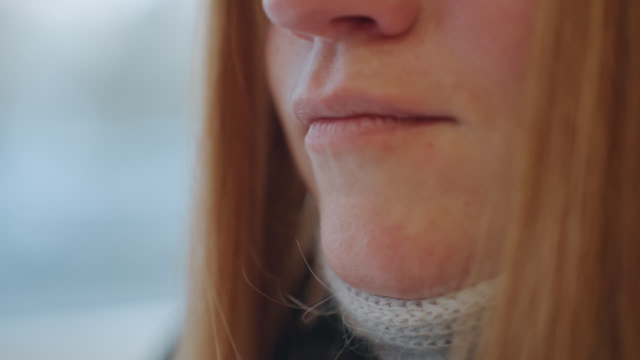 Rossa concentrata e pensierosa. Rossa caucasica con espressione contemplativa vicino alla finestra. Dettaglio ravvicinato di una donna rossa pensierosa con sciarpa lavorata a maglia e delicata illuminazione cinematografica.