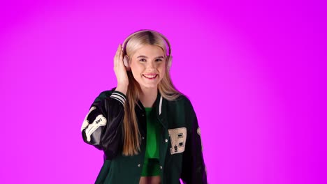 cheerful young blonde woman listening to music with headphones, dancing and thumb up gesture