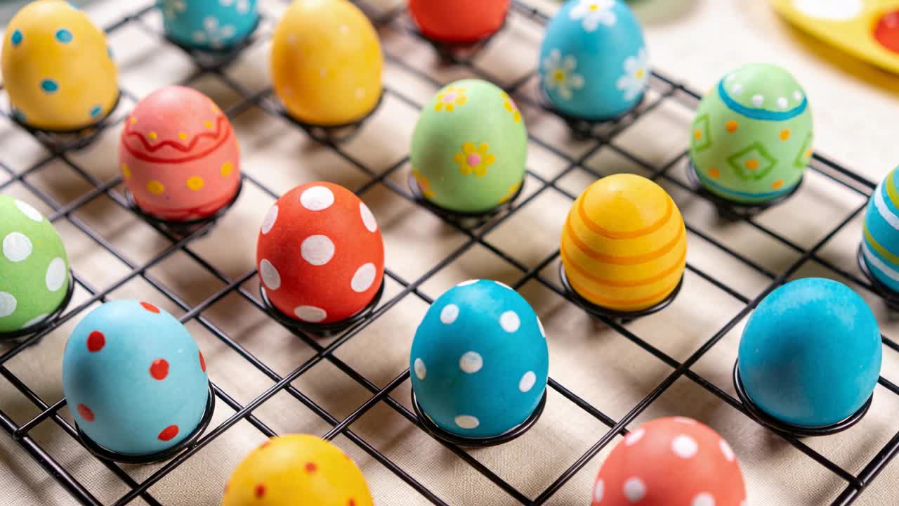 Tilting camera focusing on Easter eggs on wire rack on beige cloth, highlighting blue polka-dot egg