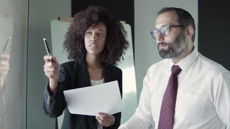 mujer de negocios afroamericana sosteniendo un bolígrafo y hablando con el director ejecutivo
