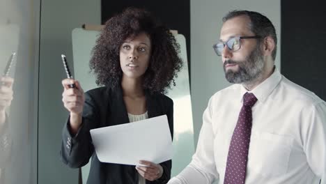 mujer de negocios afroamericana sosteniendo un bolígrafo y hablando con el director ejecutivo