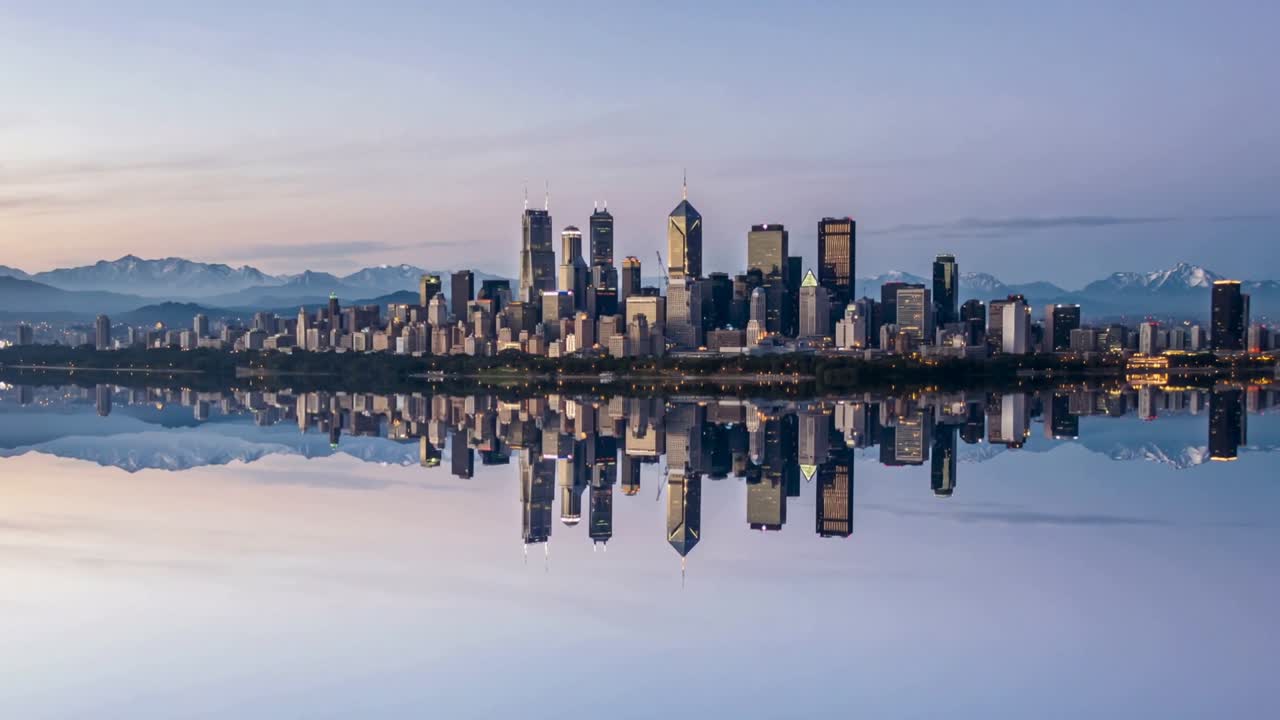 Dawn light shifting, city skyline reflecting on calm waterfront, highlighting towers' glass facades